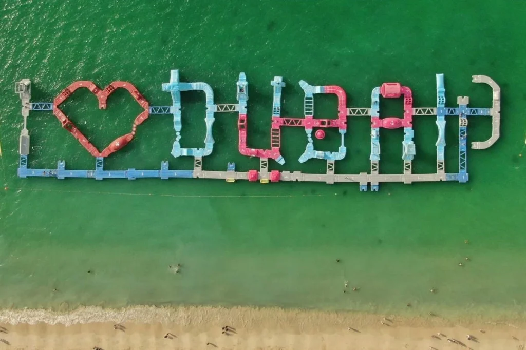 Aerial view of the Aquafun inflatable water park obstacle course in Dubai, spelling out 'I Love Dubai' in the water.